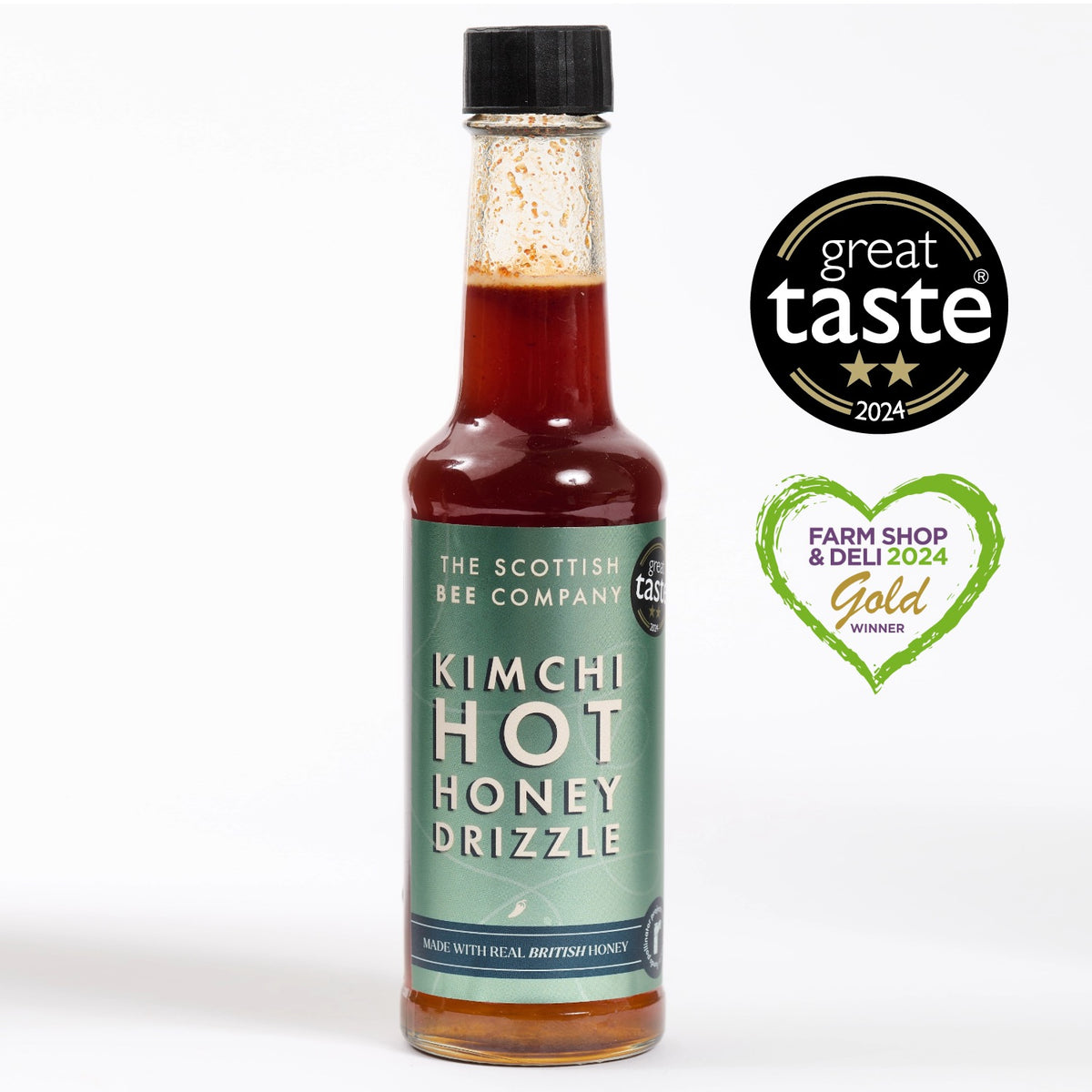 A bottle of Kimchi Hot Honey Drizzle with the label showing the product name and the award seals from Great Taste and Farm Shop & Deli 24 Gold.