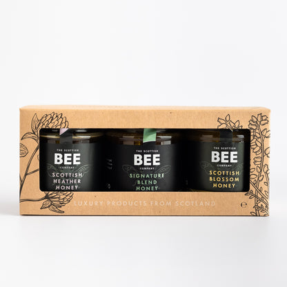 trio of honeys in a brown paper gift set on a white background