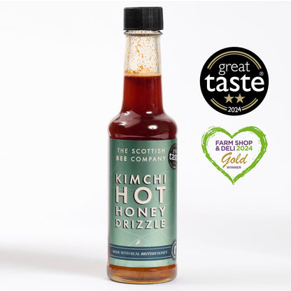 A bottle of Kimchi Hot Honey Drizzle with the label showing the product name and the award seals from Great Taste and Farm Shop &amp; Deli 24 Gold.