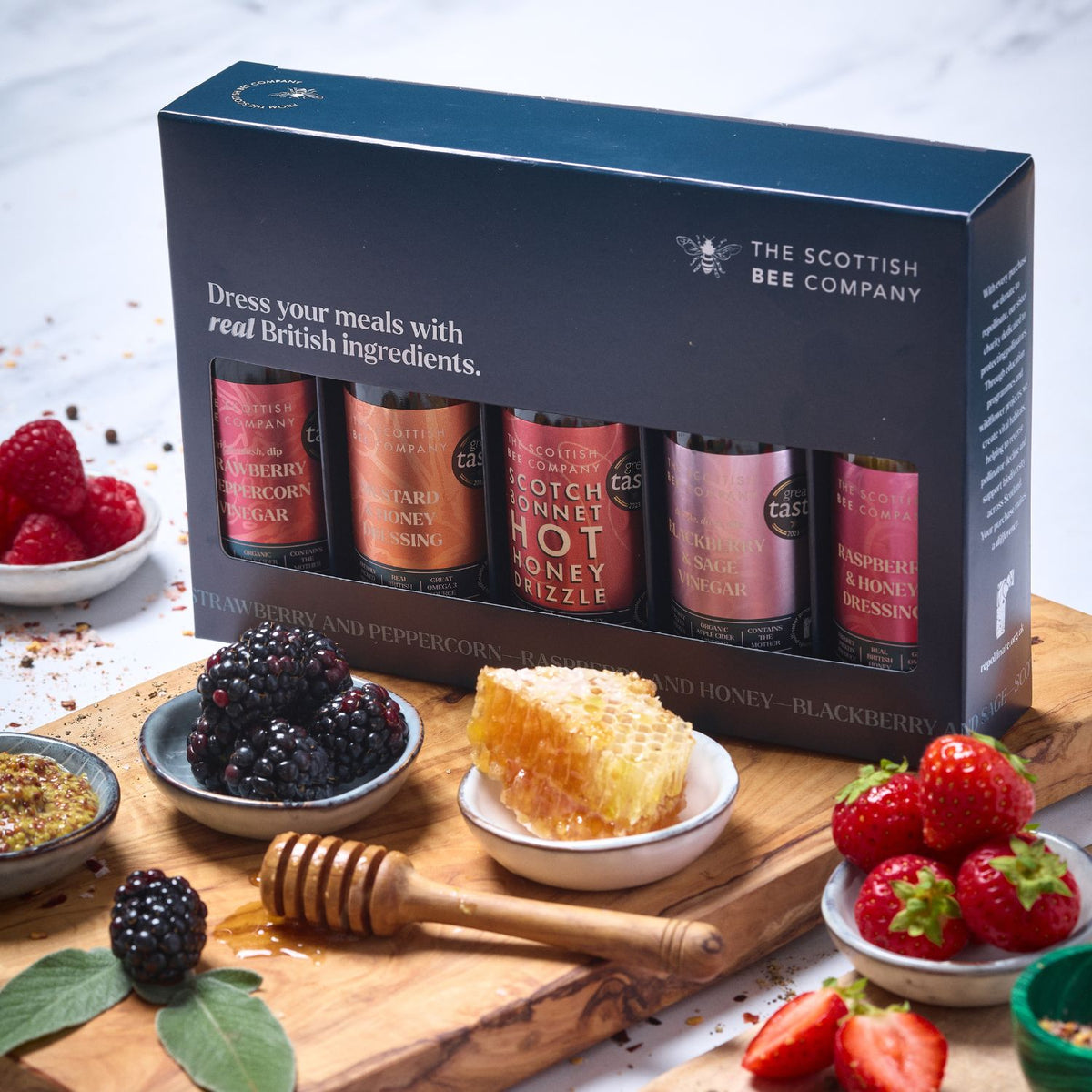Honey product set from The Scottish Bee Company with honeycomb, berries, and a wooden dipper on a wooden board.